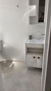 een witte badkamer met een wastafel en een spiegel bij Pousada Carmel in Ametista do Sul