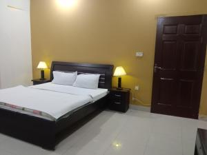 Victoria Guest House في بهاوالبور: غرفة نوم بسرير وباب ومصباحين