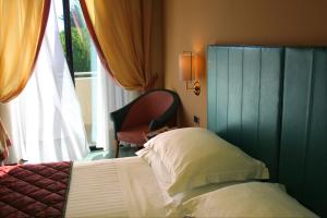a bedroom with a bed and a chair next to a window at Hotel Cristallo in Giulianova