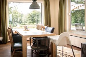 a dining room with a table and chairs and a window at Polderhuys De Veerhoek in Oostburg