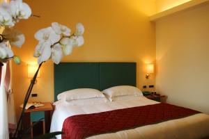 a bedroom with a bed with a green headboard and white flowers at Hotel Cristallo in Giulianova