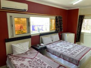 two beds in a room with red walls and windows at Isis Hostel 2 in Cairo