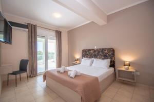 a bedroom with a large bed and a balcony at DENNIS and TANYA VILLAS in Laganas