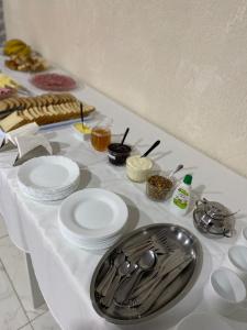 een tafel met witte borden en keukengerei erop bij Pousada Carmel in Ametista do Sul