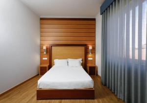 a bedroom with a bed and a large window at Montebelo Palácio dos Melos Viseu Historic Hotel in Viseu