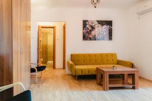 un soggiorno con un divano giallo e un tavolo di Romanian Athenaeum 1BR Apartment with Amazing View a Bucarest