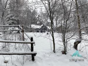 un campo cubierto de nieve con una valla y árboles en Slowlife Mátra, en Mátraszentistván