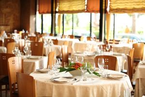 een eetkamer met witte tafels en stoelen met bloemen erop bij Hotel Cristallo in Giulianova
