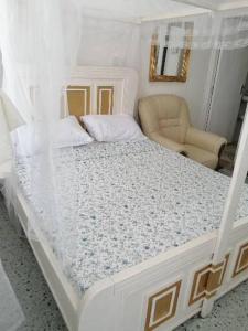 a bedroom with a white bed and a chair at Neighbourly Nest in Mombasa