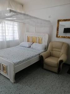 1 dormitorio con cama, silla y espejo en Neighbourly Nest en Mombasa