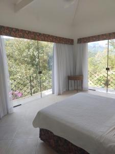 a bedroom with a large bed and large windows at Zen in Itaipava