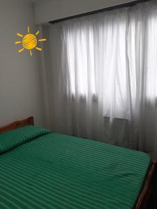 Un dormitorio con una cama verde con una señal de sol en la pared en Depto. 1 ambiente Plaza Mitre en Mar del Plata