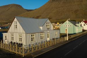 a house on the side of a road next to a mountain at Pálshús in Patreksfjörður