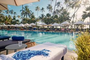 una piscina en el complejo con sillas y sombrillas en TUI BLUE Bahari Zanzibar en Pwani Mchangani