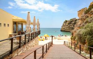 a boardwalk on a beach with umbrellas and the ocean at Apartment T2 Alvor in Alvor