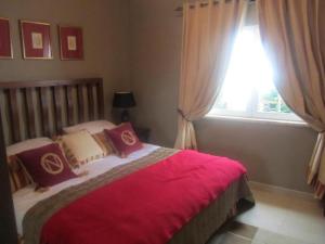 een slaapkamer met een bed met rode lakens en een raam bij Stunning 3 bed villa with pool- Golf Beach in Budens