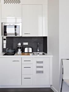 uma cozinha branca com um lavatório e um micro-ondas em VISIONAPARTMENTS Otto-Braun-Strasse - contactless check-in em Berlim