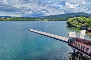 un muelle en un lago con dos sillas. en Camp Velenje, en Velenje