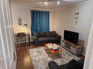 a living room with a couch and a tv at Washingtons Emerald 2 bed executive Apartment in Washington