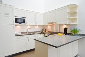 cocina con armarios blancos y encimera de granito en Walensee Apartment 80 en Unterterzen