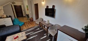 ein Wohnzimmer mit einem TV, einem Tisch und Stühlen in der Unterkunft Apartman Deluxe villa Barbora Hrabovo in Ružomberok