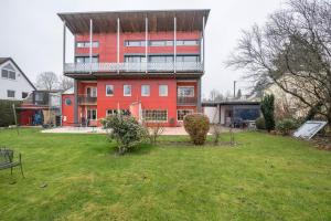 a red building with a balcony on top of a yard at Haus Rose Muc City in Munich