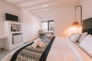 a white bedroom with a large bed with pink pillows at Mr & Mrs White Mykonos in Platis Gialos