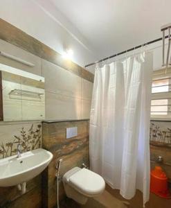 uma casa de banho com um lavatório e uma cortina de chuveiro branca em Coral Cove Beach Resort em Varkala