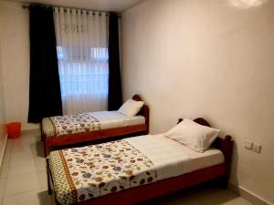 two beds in a room with a window at BIZI HOMES in Kigali