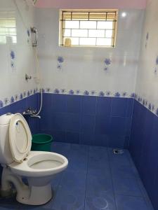 uma casa de banho em azulejos azuis com um WC e uma janela em Coral Cove Beach Resort em Varkala