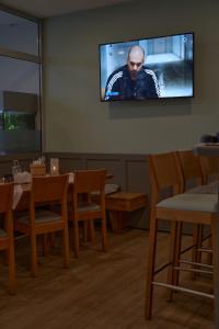 グックスハーゲンにあるHotel Auszeit im Euro Rastpark Guxhagenの壁にテレビとテーブルと椅子が備わる客室です。
