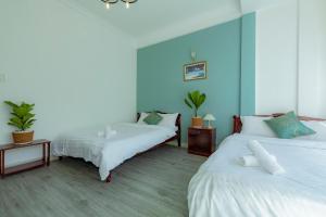 two beds in a room with blue walls at VŨ NHI HOTEL ĐÀ LẠT in Da Lat