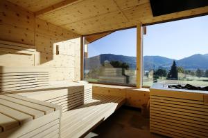 バート・ウィーゼにあるHotel Bussi Babyの木製のベンチと大きな窓が備わる客室です。
