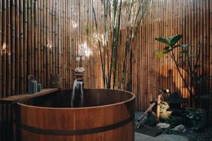 MAYU Bangkok Japanese Style Hotel في بانكوك: حوض استحمام مع نافورة أمام جدار من الخيزران