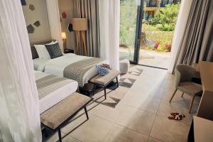 um quarto de hotel com uma cama e cadeiras e uma janela em TUI BLUE Bahari Zanzibar em Pwani Mchangani