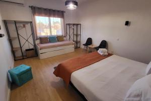 a bedroom with a bed and a couch and a window at Casa Borges in Charneca