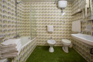 a bathroom with a toilet and a tub and a sink at Hotel Lido Mediterranee in Taormina