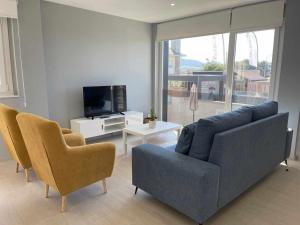uma sala de estar com um sofá azul e duas cadeiras em Adosado A 5 hab em Foz
