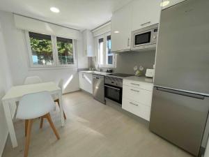 uma cozinha com electrodomésticos brancos e uma mesa e cadeira em Adosado A 5 hab em Foz