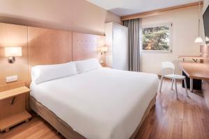 Habitación de hotel con cama blanca grande y escritorio. en B&B HOTEL Madrid Arganda en Arganda del Rey