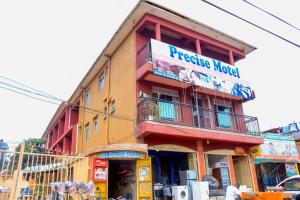un bâtiment avec un panneau sur son côté dans l'établissement Precise Motel, à Kampala