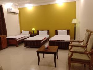 a room with three beds and a chair and a table at Victoria Guest House in Bahawalpur