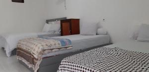 a white bedroom with two beds and a table at ADELYA HOMESTAY in Praya