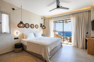 a bedroom with a bed with a view of the ocean at Aegean Village Beachfront Resort in Amoopi