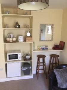 a kitchen with a microwave and a counter with stools at Bens Hollow with hot tub in Bredon