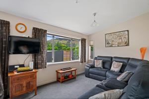 a living room with a couch and a flat screen tv at Thyme Away - Clyde Holiday Home in Clyde