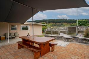 an umbrella on a patio with a table and benches at Thyme Away - Clyde Holiday Home in Clyde