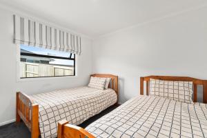two beds in a room with a window at Puna Rise - Taupo Holiday Home in Taupo