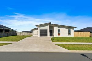 a white house with a driveway in a yard at Puna Rise - Taupo Holiday Home in Taupo