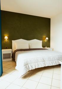 een slaapkamer met een groot wit bed en een groene muur bij Tuo Hotel in Polignano a Mare